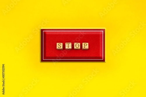 黄色い背景の四角いSTOPの英語ブロックの赤いボタン photo