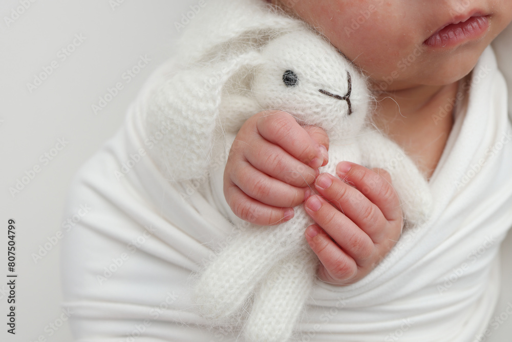 Sleep of a newborn in the first days of life. Portrait of a newborn one week old baby with a cute soft toy plush white rabbit on a white background. Cute little fingers and hands of a child. Sleep of a newborn in the first days of life. Portrait of a newborn one week old baby with a cute soft toy plush white rabbit on a white background. Cute little fingers and hands of a child.