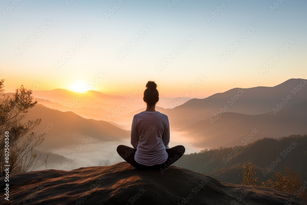 person meditating on mountain overlooking misty valley at sunset