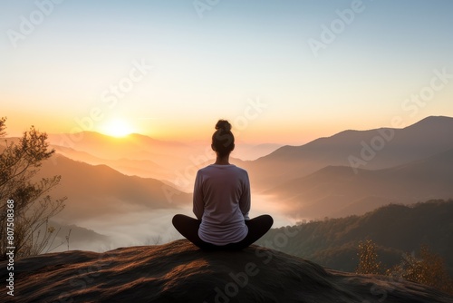 person meditating on mountain overlooking misty valley at sunset