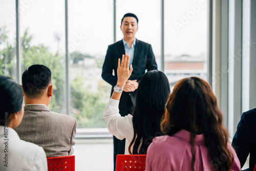 A diverse audience in a conference raises their hands for questions, voting, or volunteering, emphasizing teamwork and audience interaction during this corporate event.