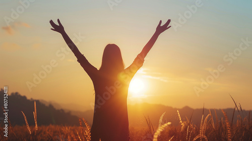 Silhouette of a woman with hands raised in the sunset concept for religion  worship  prayer and praise  Religious concepts 