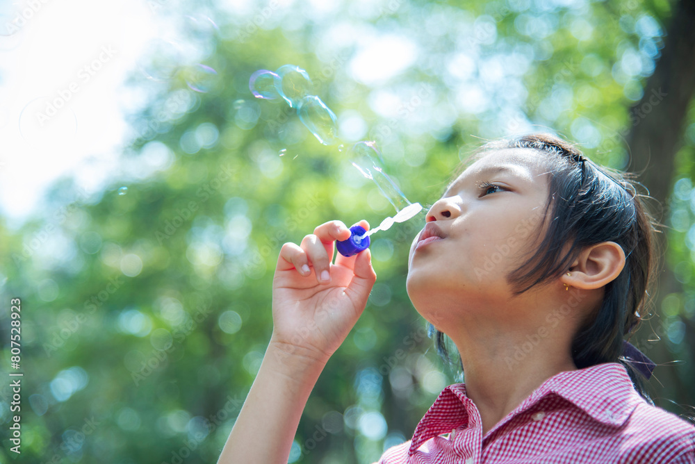 Adorable happy cute girl playful foam bubbles in green playground in summer outdoors. Funny Cheerful girl in the park with happy times. Adorable happy cute girl playful foam bubbles in green playground in summer outdoors. Funny Cheerful girl in the park with happy times.