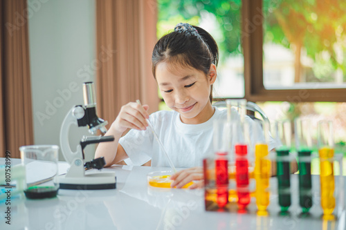 little scientist looking through a microscope and test tubes filled with chemicals for learning about science and experiments.