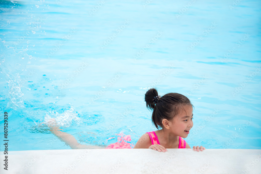 Toddler girl have fun swimming pool summer time with swimwear in blue water at hotel swimming pool outdoor. Kid swim playful water splash with happiness on summer vacation. Happy girl swim concept Toddler girl have fun swimming pool summer time with swimwear in blue water at hotel swimming pool outdoor. Kid swim playful water splash with happiness on summer vacation. Happy girl swim concept
