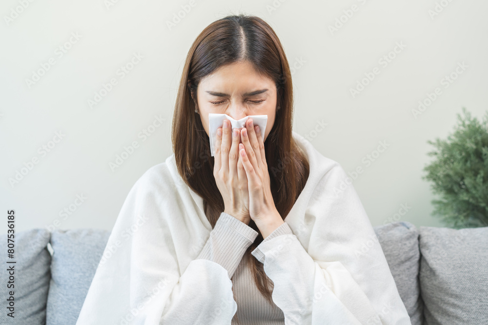 Sick, coronavirus or covid, tired asian young woman have a fever, flu and hand in use tissues paper sneezing nose, runny while sitting on sofa, couch at home. Health care with disease, pandemic virus Sick, coronavirus or covid, tired asian young woman have a fever, flu and hand in use tissues paper sneezing nose, runny while sitting on sofa, couch at home. Health care with disease, pandemic virus
