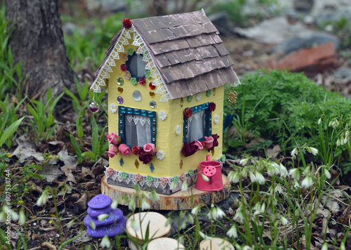Cute fairy doll house with spring flowers outside in the garden. Lovely miniature for greeting cards, wedding or birthday concept, real estate, downsizing, home ownership © samiramay