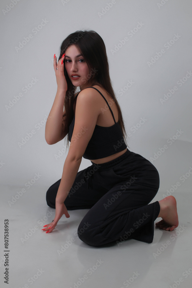 Portrait of a beautiful fashion model in the studio on a light background, wearing a black short clothes and trousers, barefoot Portrait of a beautiful fashion model in the studio on a light background, wearing a black short clothes and trousers, barefoot