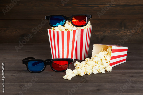 Popcorn, 3D glasses for cinema time on dark wooden background.