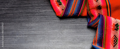 Bright multicolor tablecloth on wooden table for background. Fabric texture. Wooden texture. Copy space. Top view