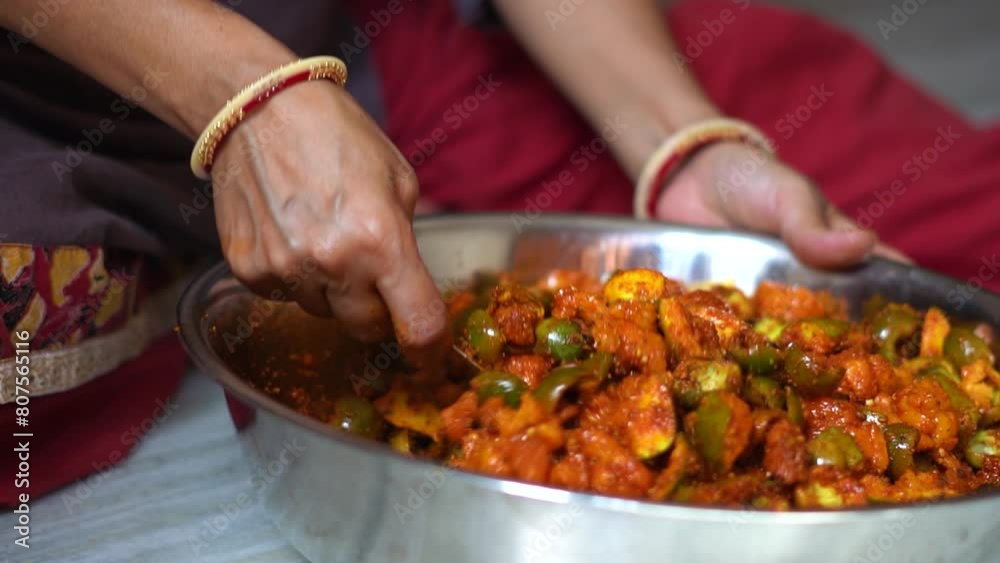 Hands of Indian woman wearing bangles mixing raw mangoes with spices to make Mango pickles. Homemade organic pickle. Female preparing food in kitchen. An Indian housewife making pickle, household work Hands of Indian woman wearing bangles mixing raw mangoes with spices to make Mango pickles. Homemade organic pickle. Female preparing food in kitchen. An Indian housewife making pickle, household work