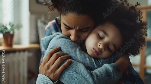 Young mom embracing and calming her child while he in bad mood or upset feelings photo