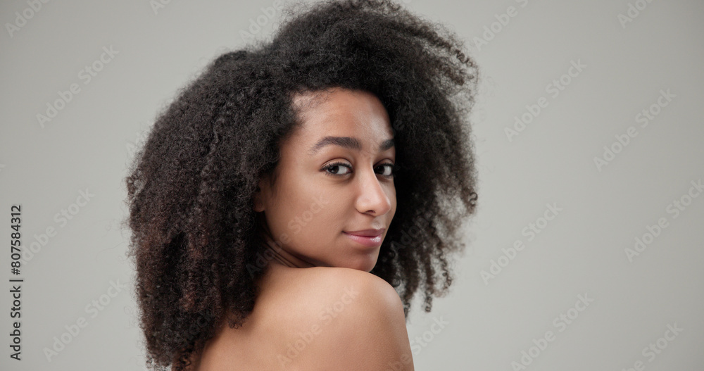 Beauty and Healthcare concept - Beautiful African American woman with curly afro hairstyle hair and clean, healthy skin on gray studio background posing and looking at camera Beauty and Healthcare concept - Beautiful African American woman with curly afro hairstyle hair and clean, healthy skin on gray studio background posing and looking at camera