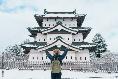 Woman tourist sightseeing Hirosaki Castle in winter, happy traveler travel Hirosaki city, Aomori Prefecture, Tohoku, Japan. Landmark and famous for tourist attraction. Japan travel and vacation photo
