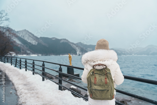 Woman tourist sightseeing golden Tatsuko statue and Lake Tazawa. Traveler travel in Semboku city, Akita Prefecture, Japan. Landmark for tourist attraction in Tohoku Region. Japan travel and vacation photo
