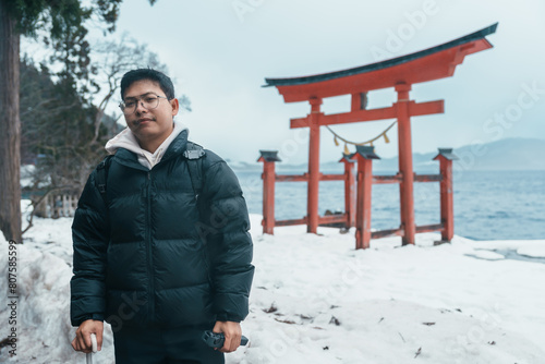 man  tourist sightseeing Japanese Torii gate  Shrine and lake Tazawa. Traveler travel in Semboku city, Akita Prefecture, Japan. Landmark for tourist attraction in Tohoku. Japan travel and vacation photo