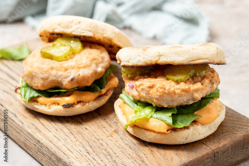 two salmon fishburgers with pickles on top photo