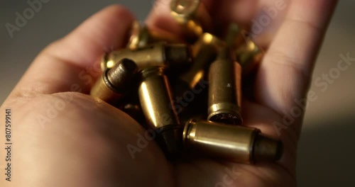 Close-up of a fistful of empty bullet shell casings being held in one hand. photo