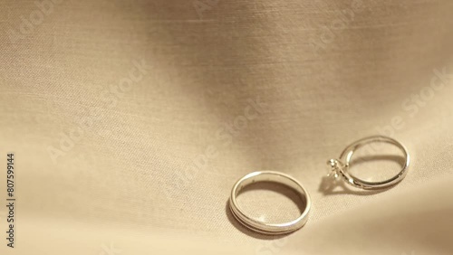 Dropping a pair of engagement rings made of platinum and diamonds on a cloth laid on a table.