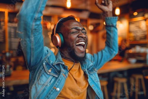 Happy young man dancing and singing while listening to music in headphones at home. photo