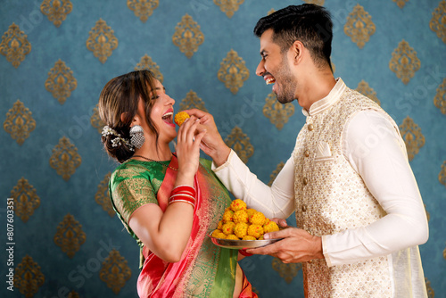 Young Romantic Couple In Indian Ethnic Wear Eating Laddu On Diwali Occasion.
