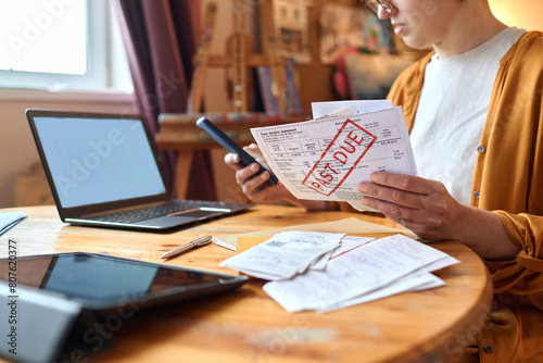 Close up of woman sorting past due bills and debt notices while managing finances, copy space
