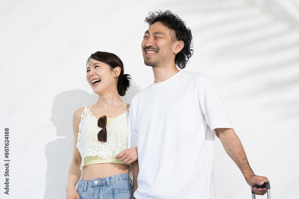 Naklejka premium 夏のバカンスに行くスーツケースを持った日本人(アジア人）カップル 海外旅行や新婚旅行, ハネムーンや南国に行くイメージ