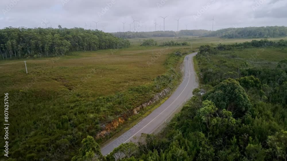 Aerial shot of regional road with white parked car and wind farm in background in Tasmania, Australia - travel road trip concept Aerial shot of regional road with white parked car and wind farm in background in Tasmania, Australia - travel road trip concept