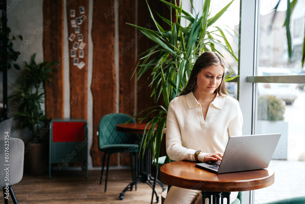 Woman Sitting at Table Using Laptop Computer Woman Sitting at Table Using Laptop Computer