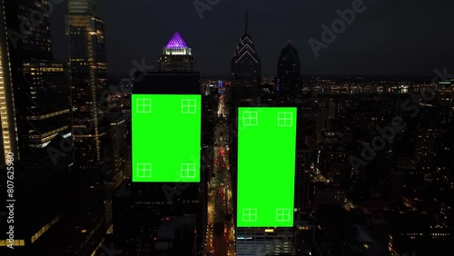 Green screen animated on dark skyscrapers in American city at night. Aerial dolly forward towards billboards with tracking points.