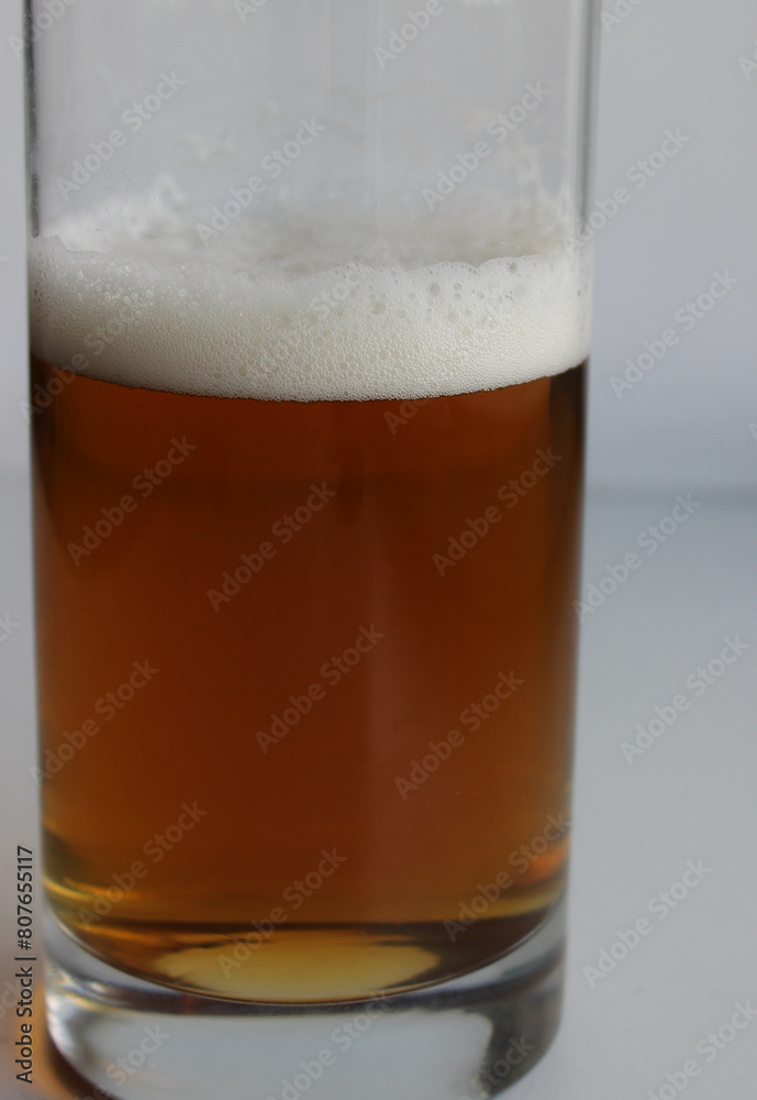 Beer glass without handle half filled with craft brown ale closeup view Beer glass without handle half filled with craft brown ale closeup view