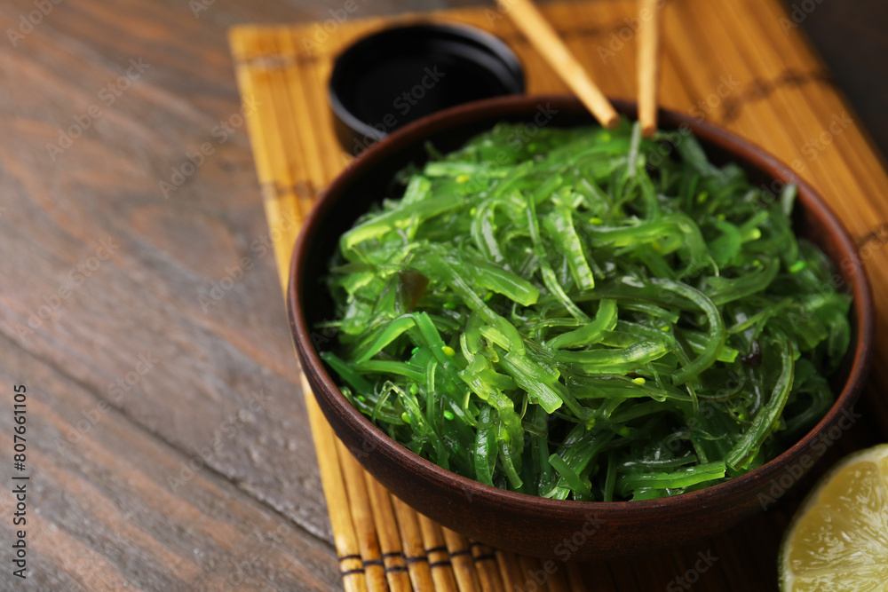 Tasty seaweed salad in bowl served on wooden table, closeup Tasty seaweed salad in bowl served on wooden table, closeup