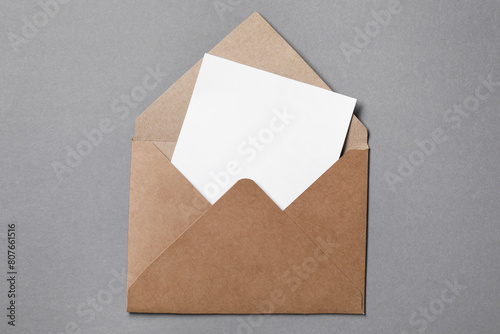 Blank sheet of paper in open letter envelope on grey background, top view © New Africa