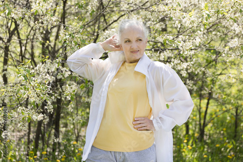 lifestyle portrait senior woman  with gray hair relaxes in a flowering garden in spring. spends time in nature. copy space. greyhairdontcare. Hanami