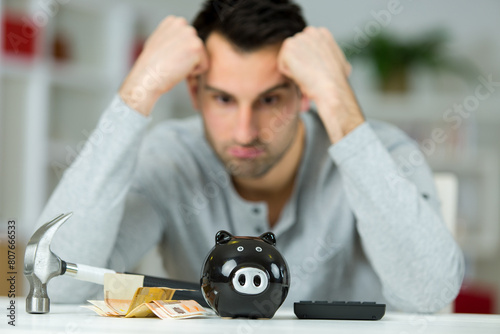 man depressed at amount of money in his piggy bank