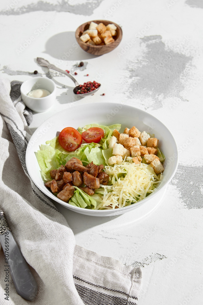 Fresh Caesar Salad with Grilled Chicken, Shaved Cheese, Croutons, and Sliced Tomatoes on a White Textured Background Fresh Caesar Salad with Grilled Chicken, Shaved Cheese, Croutons, and Sliced Tomatoes on a White Textured Background