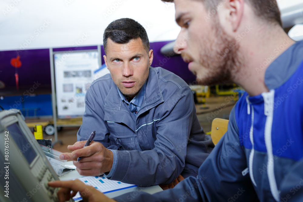 engineer teaching apprentice to use machine