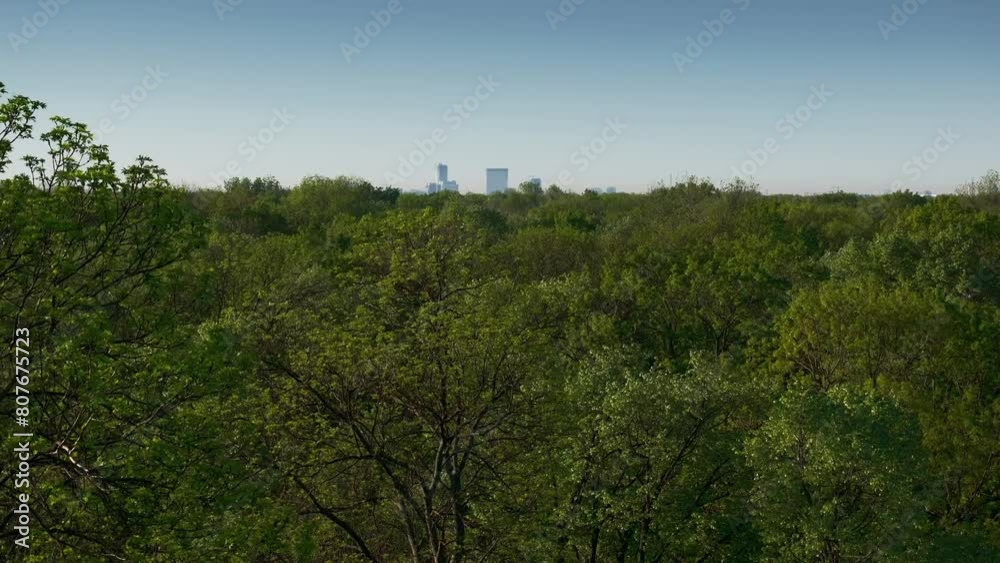Bucharest from above. Aerial 4k video landscape of north part of Bucharest, view from Baneasa Forest with green trees in foreground. Unique perspective of Bucharest, capital of Romania. Bucharest from above. Aerial 4k video landscape of north part of Bucharest, view from Baneasa Forest with green trees in foreground. Unique perspective of Bucharest, capital of Romania.