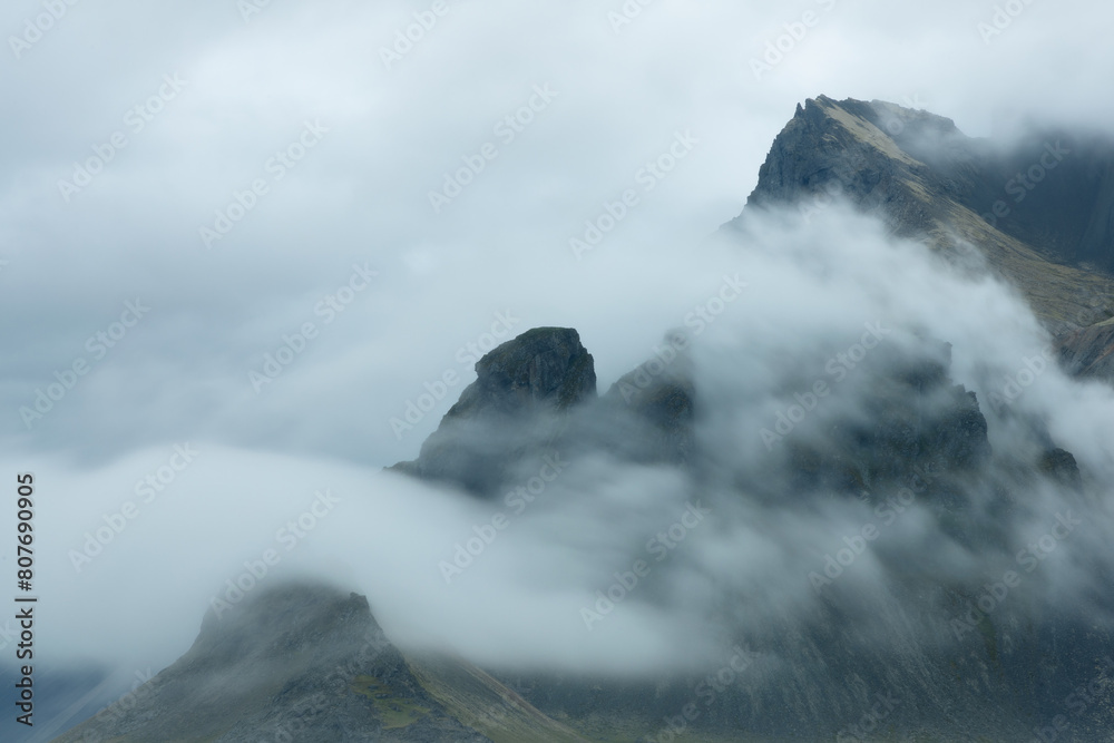 Atmospheric Clouds breaking over the ridge of Vestrahorn mountains on a overcast day in Stokksnes, southeast Iceland