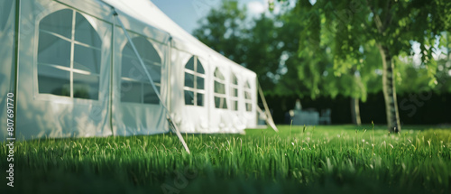 A spacious event tent stands on a lush lawn awaiting guests under clear skies.