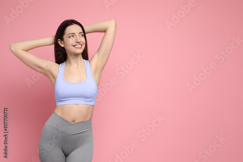 Happy young woman with slim body posing on pink background, space for text
