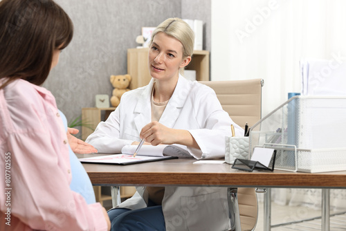 Doctor consulting pregnant patient at table in clinic