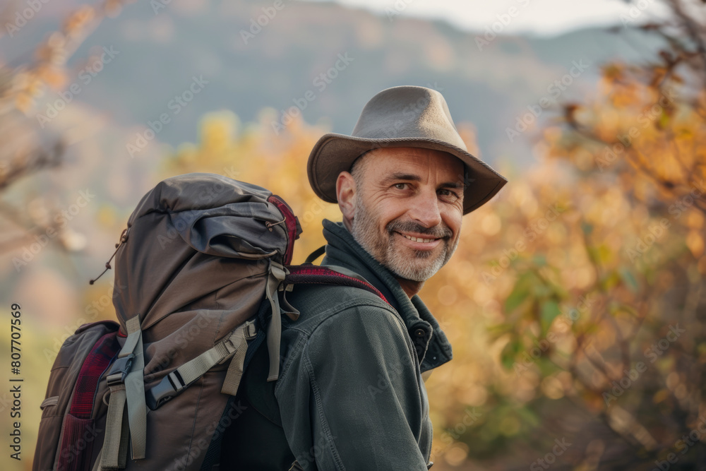 Smiling hiker with a hat looking over his shoulder amidst autumn foliage. Smiling hiker with a hat looking over his shoulder amidst autumn foliage.