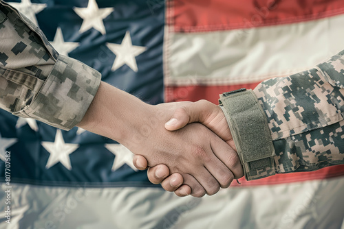 Military hands clasping in a firm handshake over the American flag symbolizing unity and partnership.