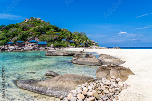 Picturesque tropical scenic landscape of Koh Nang Yuan Island in Thailand, near Koh Tao. An empty sand beach and crystal-clear sea water, with a hotel resort on the hillside by the shore