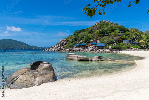 Peaceful tropical scenic landscape of Koh Nang Yuan Island in Thailand, near Koh Tao. An empty sand beach and crystal-clear sea water, with a hotel resort on the hillside by the shore