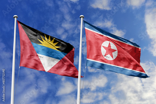  3d illustration. Antigua and Barbuda and North Korea Flag waving in sky. High detailed waving flag. 3D render. Waving in sky. Flags fluttered in the cloudy sky. photo