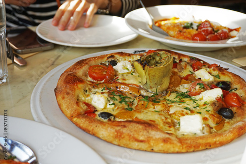 Close up Mozzarella cheese pizza topped with tomato, sweet pepper, olive and artichoke