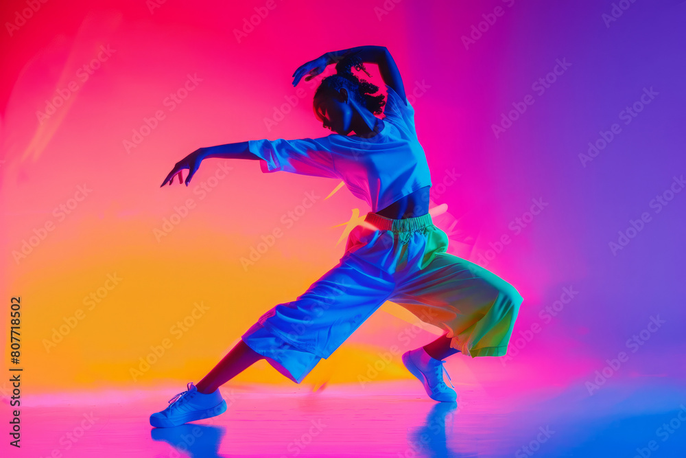 Female dancer on neon colored background. Woman in dynamic pose dancing, showing artistic expression