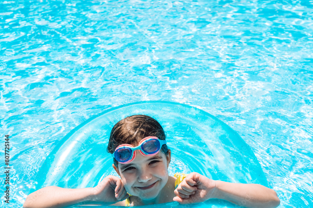 Fototapeta premium A little girl with an inflatable circle jumped into the pool. A cute kid in a swimsuit
